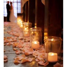 candles are lined up on the floor with petals