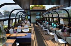 the inside of a boat with tables and chairs on each side, along with lots of windows