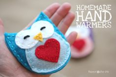 a hand holding a small felt owl with a heart on it