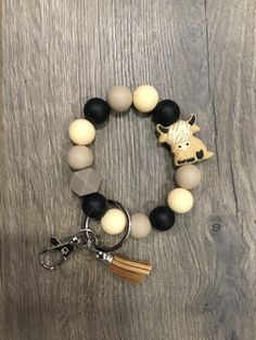 a black, white and grey beaded bracelet with a wooden cow charm on it