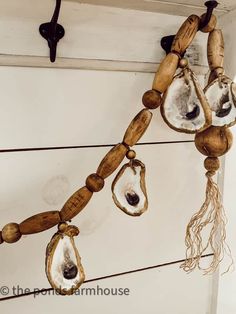 several pieces of wood hanging from the side of a wall with shells attached to it