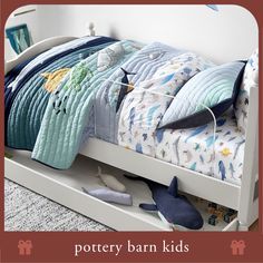 a child's bed with blue and white bedspread, pillows and toys