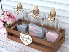 three glass bottles filled with bath salts on top of a wooden tray