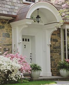 a white door and some flowers in front of a brick building with an arched doorway