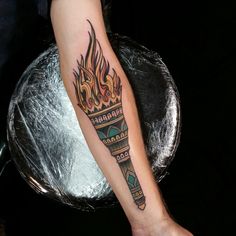 a person with a tattoo on their arm that has flames coming out of the top