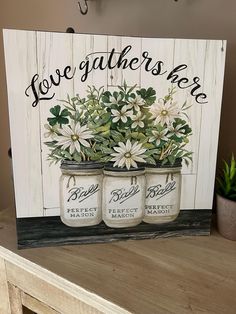 two mason jars with daisies in them are on a shelf next to a potted plant