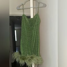 a green dress hanging on a hanger next to a door in a room with white walls