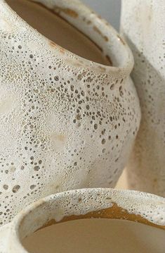 two white vases sitting on top of a table next to each other with holes in them