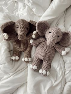 two crocheted elephants laying on top of a bed