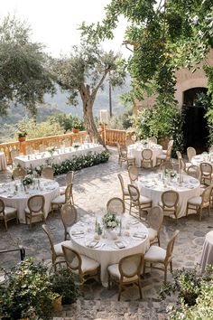 an outdoor dining area with tables and chairs set up for a formal function in the garden