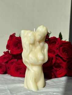 a candle that is sitting in front of some red roses