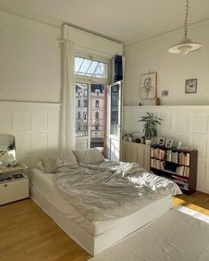 a bedroom with a bed, dresser and window in the corner is shown on a wooden floor