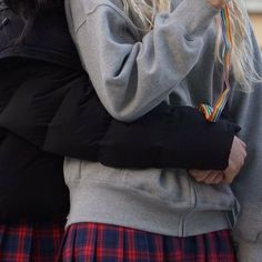 two girls are hugging each other while one girl is holding her hand over her shoulder