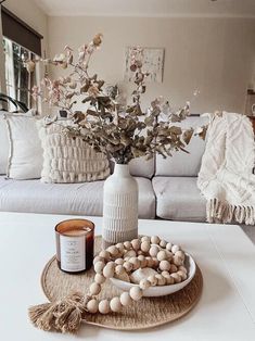 a white vase filled with flowers sitting on top of a table next to a candle