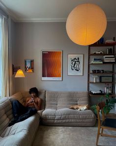 a man sitting on top of a couch in a living room next to a window