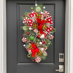 a christmas wreath with candy canes and ornaments hanging on a front door or entrance