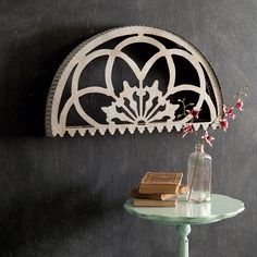 a table with a vase and book on it next to a wall mounted shelf in the corner