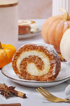 a cinnamon roll sitting on top of a white plate next to other pumpkins and spices