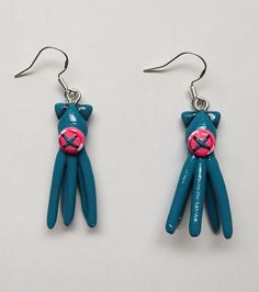 pair of blue cat earrings with pink eyeballs on white background, close up view