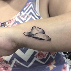 a woman's arm with a hat tattoo on the left side of her arm