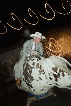 a man riding on the back of a cow at night