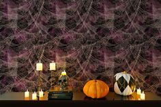 a table topped with candles and pumpkins next to a wall covered in spider web