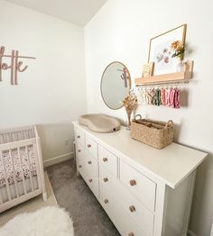 a baby's room with a dresser, crib and mirror on the wall