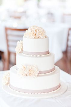 a three tiered wedding cake with flowers on top