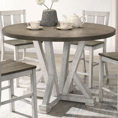 a round table with two chairs and a vase on it in a white dining room