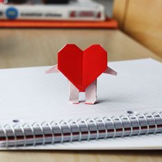 a red heart shaped origami on top of a notebook