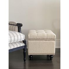 a white ottoman sitting next to a black chair on top of a hard wood floor