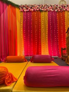 two beds covered in orange and pink sheets next to a wall with flowers on it