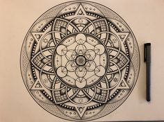 a pen and ink drawing of a flower in the middle of a circular design on paper