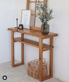 a wooden table topped with a vase filled with flowers next to a mirror and framed pictures