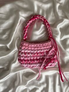 a pink purse sitting on top of a white sheet