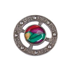 a silver brooch with multicolored glass in the center on a white background