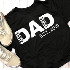 a black shirt with the words dad est 2010 on it next to a pair of sneakers