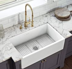 a white kitchen sink sitting under a window next to a faucet and counter top