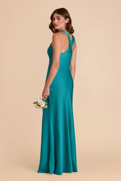 a woman in a teal dress with her back to the camera, holding a bouquet