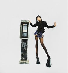 a woman standing next to a parking meter with her hands in the air while wearing black tights