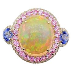 The Following Items we are offering is this Rare Important Radiant 18KT Gold LARGE Glittering and Sparkling Magnificent Fancy Multi colored Opal and Pink Sapphire Blue Sapphire White Diamond Ring. Ring Contains a Beautiful Gorgeous Large Round Opal surrounded with a Halo of Glittering Fancy Colored Pink Sapphires and Diamonds with 2 Blue Sapphires!!! Stones are Very Clean and Extremely Fine! T.C.W. Approx 7.50CTS!!! This Magnificent Ring is from a Private Top Manufacturer that sold to Important