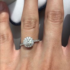 a woman's hand with a diamond ring on top of her finger and the other hand holding an engagement ring