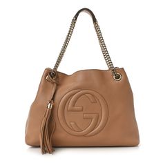 This is an authentic GUCCI Pebbled Calfskin Medium Soho Chain Shoulder Bag in Camelia. This stylish tote is crafted of pebbled beige leather. The bag features a light gold chain link shoulder strap with shoulder pads and a removable gold-knobbed tassel, and a prominent interlocking GG logo stitched on the front. The top is open to a coarse linen fabric interior with zipper and patch pockets. Gucci Tote Bag, Gucci Monogram, Gucci Tote, Gg Logo, Gucci Shoulder Bag, Shopper Tote, Shopping Tote, Chain Shoulder Bag, Black Tote Bag