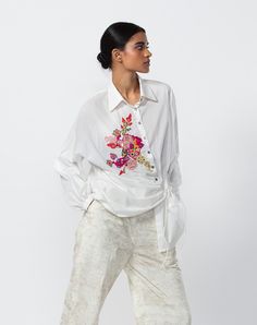 a woman in white shirt and pants with flower embroidery on the front, side view