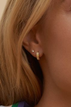 a close up view of a woman's ear with two small gold hoops