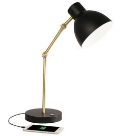 a black and gold desk lamp next to an iphone on a white background with the light turned off