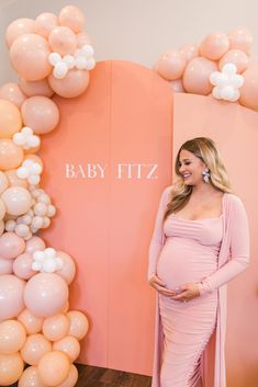 a pregnant woman standing in front of balloons