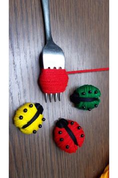 four little ladybugs sitting on top of a wooden table next to a fork