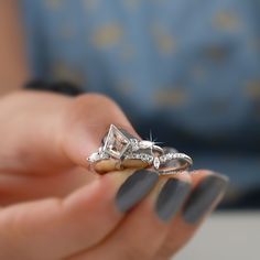 a woman's hand holding an engagement ring with a diamond on top and two diamonds in the middle