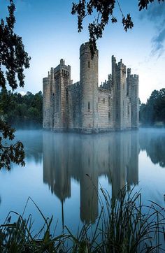 a castle sitting on top of a lake surrounded by trees